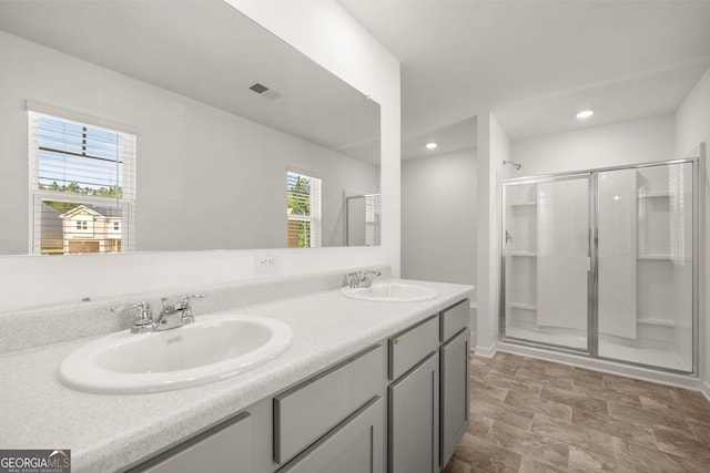 bathroom featuring a shower with door and vanity