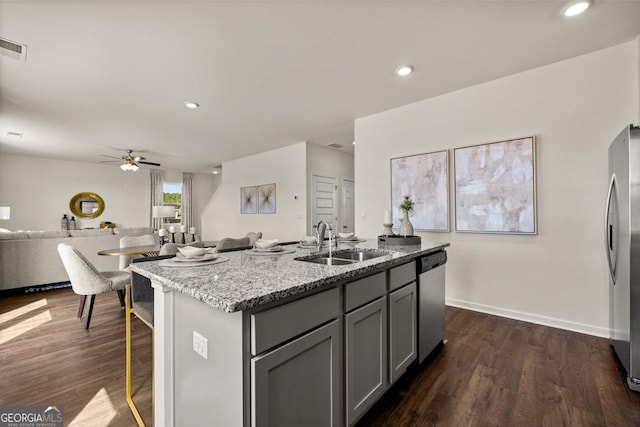 kitchen featuring appliances with stainless steel finishes, gray cabinetry, dark wood-type flooring, an island with sink, and sink