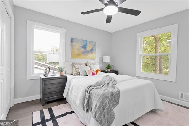 bedroom featuring ceiling fan, wood finished floors, visible vents, and baseboards