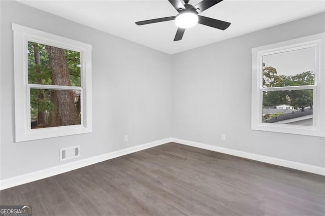 empty room with baseboards, visible vents, dark wood finished floors, and a ceiling fan