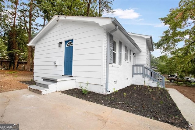 view of property exterior with crawl space and brick siding