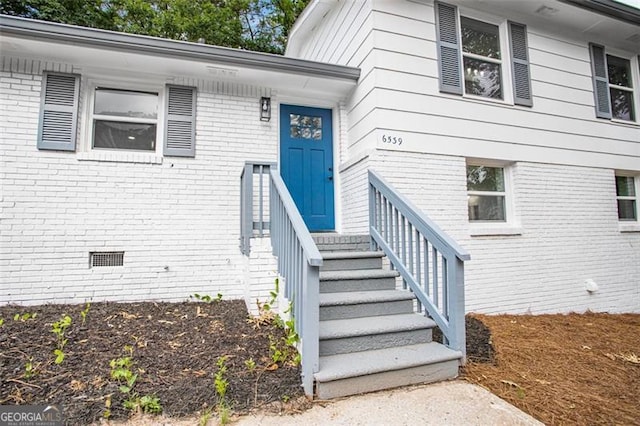 view of exterior entry featuring crawl space and brick siding