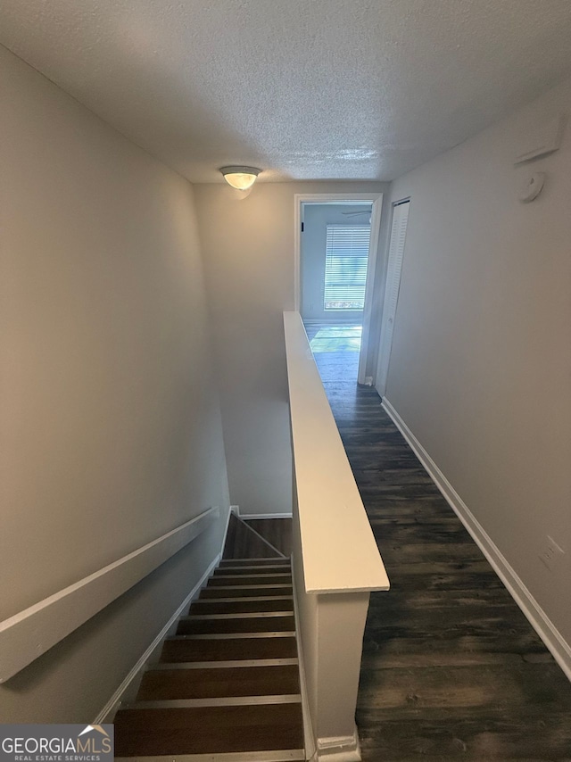 staircase featuring a textured ceiling and hardwood / wood-style floors