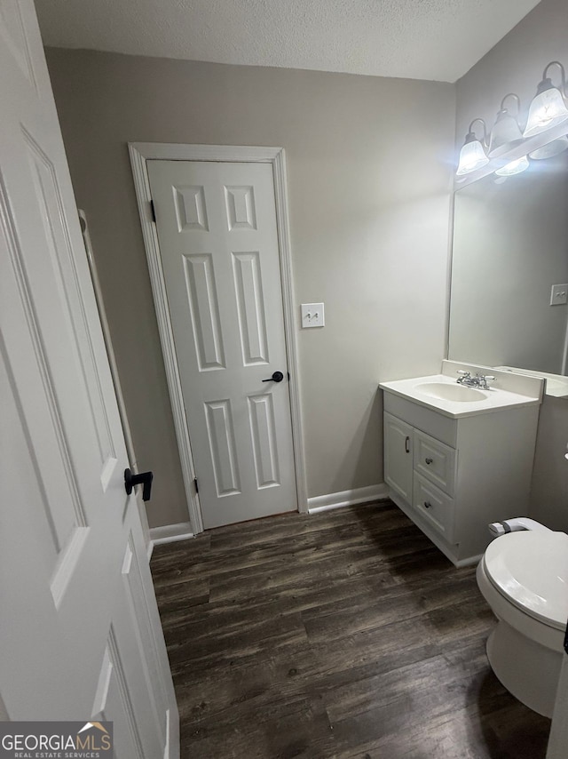 bathroom featuring toilet, vanity, a textured ceiling, and hardwood / wood-style floors