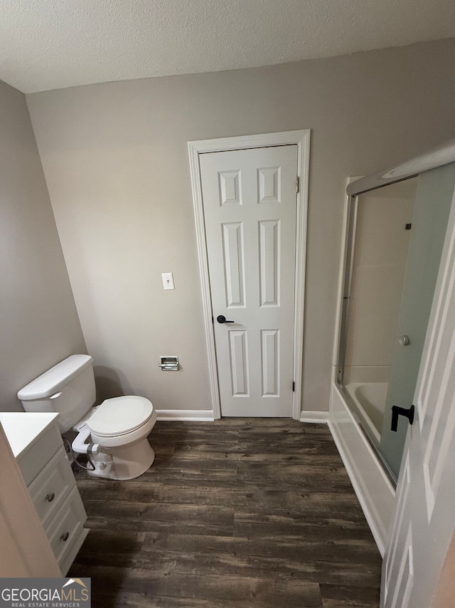 full bathroom featuring hardwood / wood-style flooring, toilet, a textured ceiling, vanity, and shower / bath combination with glass door