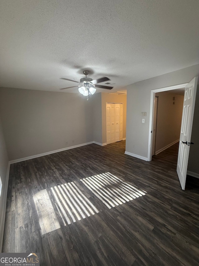 unfurnished bedroom featuring ceiling fan, dark wood-type flooring, and a textured ceiling