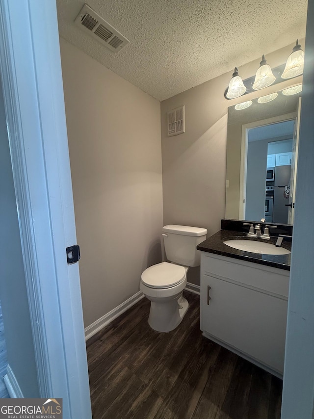 bathroom with toilet, vanity, wood-type flooring, and a textured ceiling