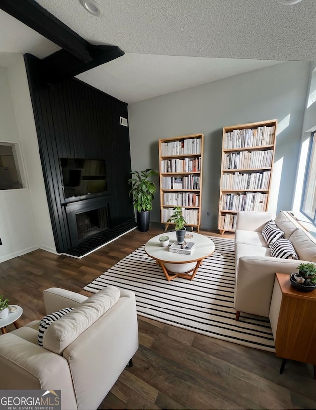 living room with dark wood-type flooring, a large fireplace, and a textured ceiling