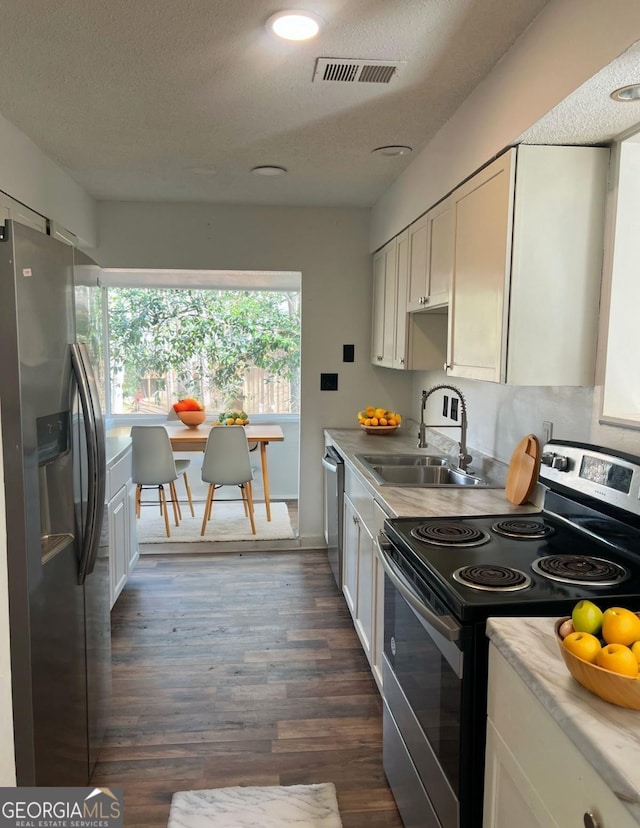 kitchen with stainless steel appliances, a textured ceiling, white cabinets, dark hardwood / wood-style flooring, and sink