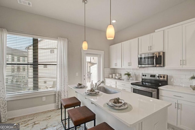 kitchen with white cabinetry, stainless steel appliances, a sink, and light countertops