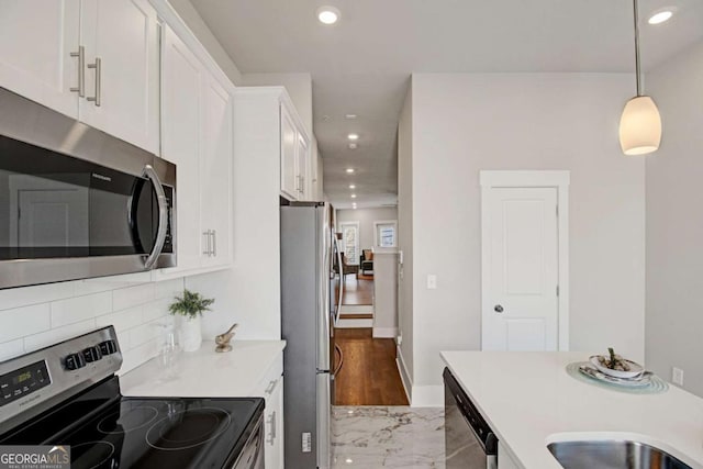 kitchen with white cabinetry, marble finish floor, light countertops, appliances with stainless steel finishes, and hanging light fixtures