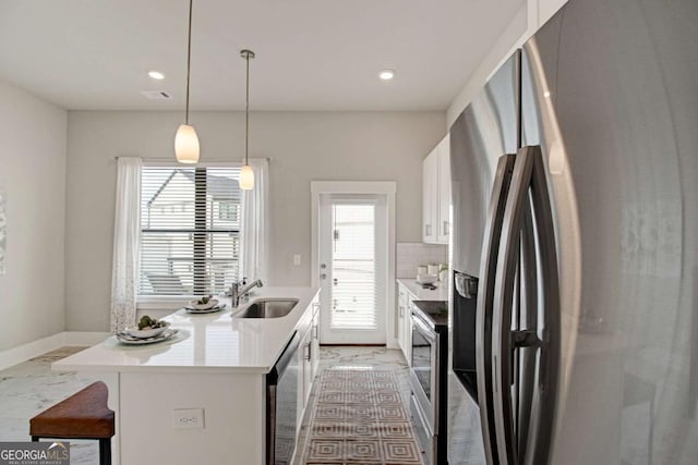 kitchen featuring appliances with stainless steel finishes, a kitchen island with sink, light countertops, white cabinetry, and a sink