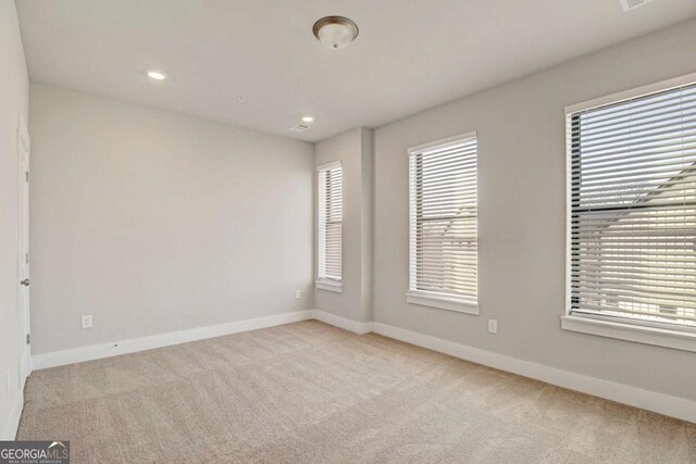 unfurnished room with light carpet, plenty of natural light, and baseboards