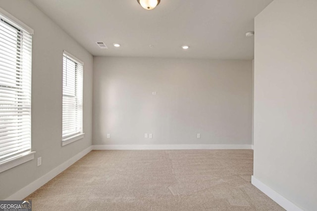 spare room featuring recessed lighting, light colored carpet, visible vents, and baseboards