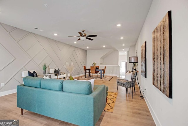 living area featuring light wood-style flooring, an accent wall, a decorative wall, and recessed lighting