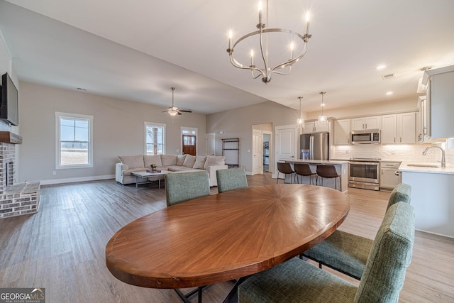 dining space featuring visible vents, ceiling fan with notable chandelier, light wood-style flooring, and baseboards