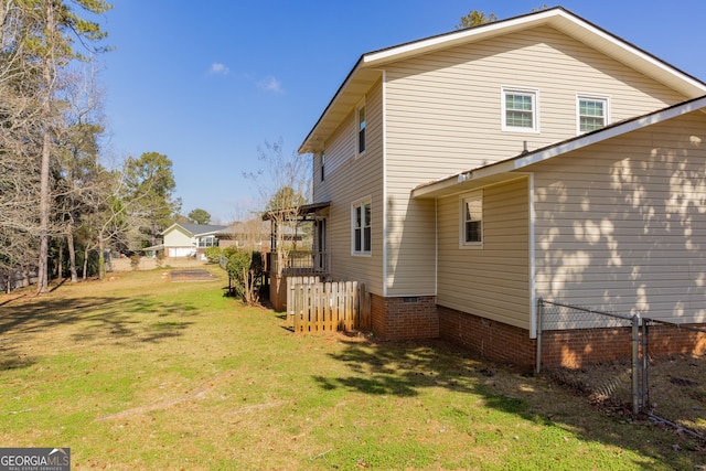 view of home's exterior with crawl space, a lawn, and fence