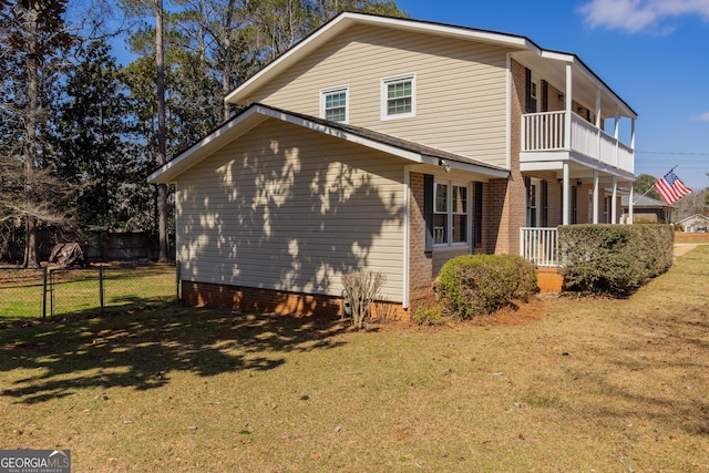 view of side of home with a lawn, a balcony, and fence