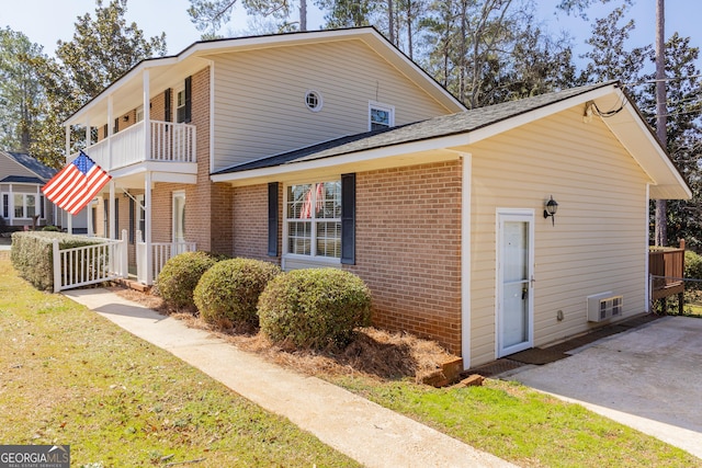 view of side of home with brick siding, fence, and a balcony