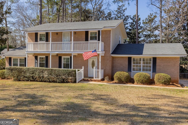 view of front facade featuring brick siding, a front lawn, and a balcony