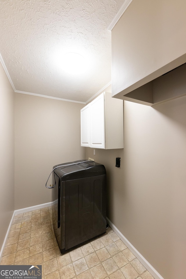 washroom with baseboards, washer / clothes dryer, cabinet space, and crown molding