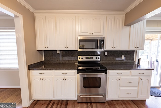 kitchen featuring appliances with stainless steel finishes, a healthy amount of sunlight, wood finished floors, and white cabinets