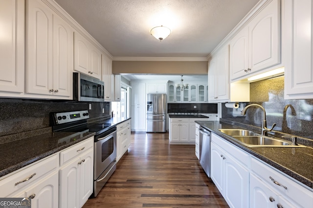 kitchen with stainless steel appliances, white cabinets, a sink, and glass insert cabinets