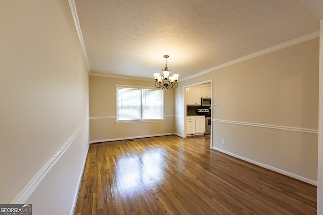 interior space with ornamental molding, wood finished floors, baseboards, and an inviting chandelier