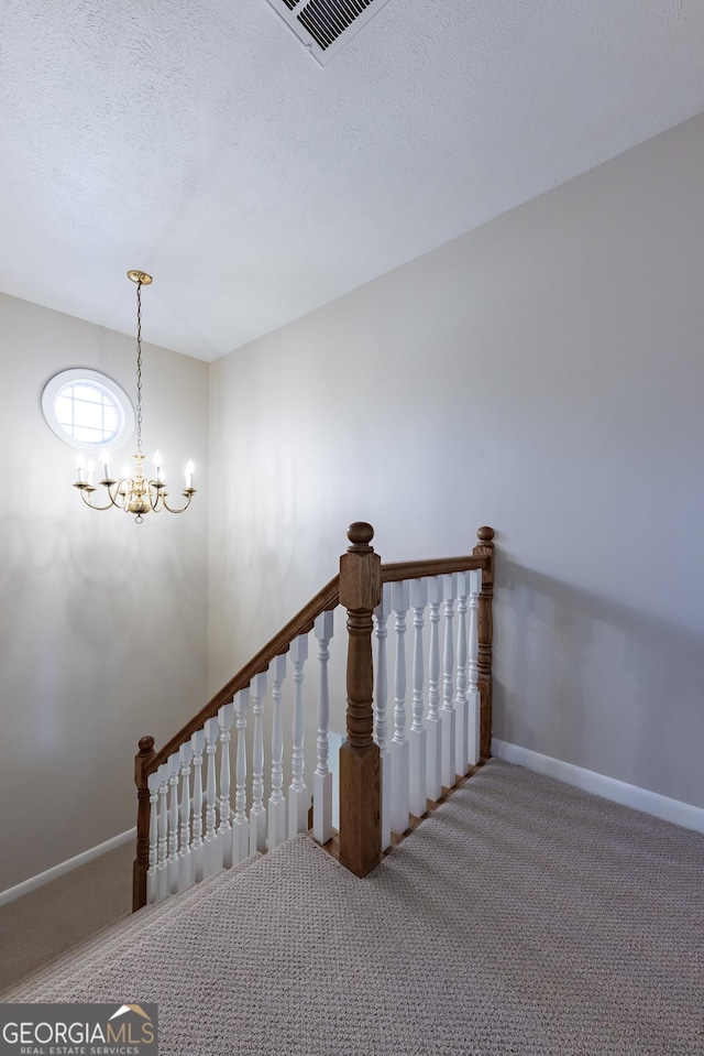 stairs featuring baseboards, visible vents, carpet, a textured ceiling, and a chandelier