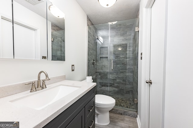 full bath featuring a textured ceiling, toilet, visible vents, vanity, and a stall shower