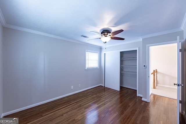 unfurnished bedroom with baseboards, visible vents, dark wood finished floors, crown molding, and a closet