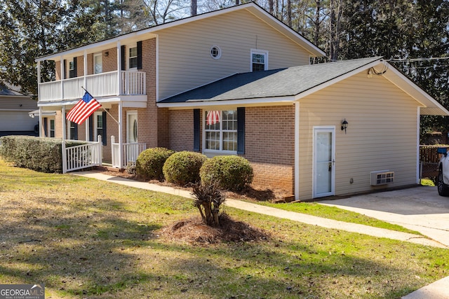 view of front of house with a balcony, a front yard, and brick siding