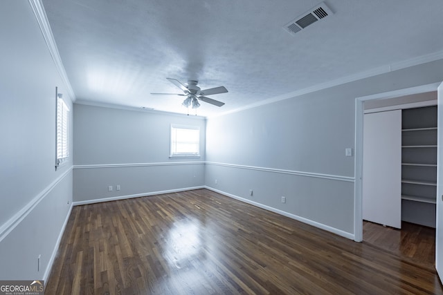 unfurnished bedroom featuring dark wood finished floors, crown molding, visible vents, a ceiling fan, and baseboards