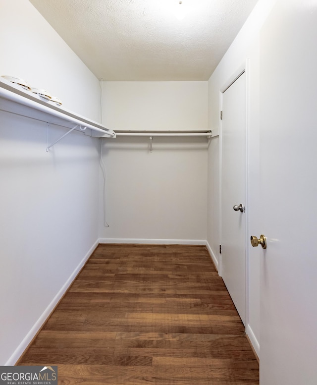 walk in closet with dark wood-style flooring