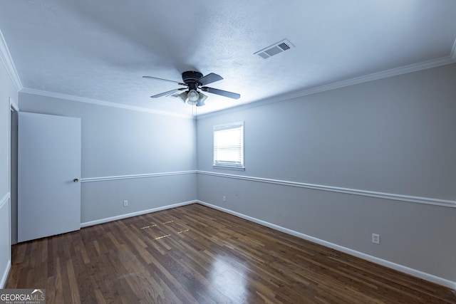 empty room with crown molding, dark wood finished floors, visible vents, and baseboards