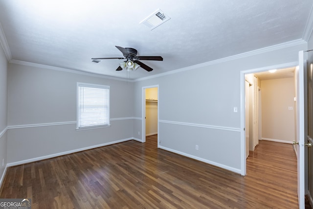 spare room featuring dark wood-style floors, visible vents, ornamental molding, a ceiling fan, and baseboards