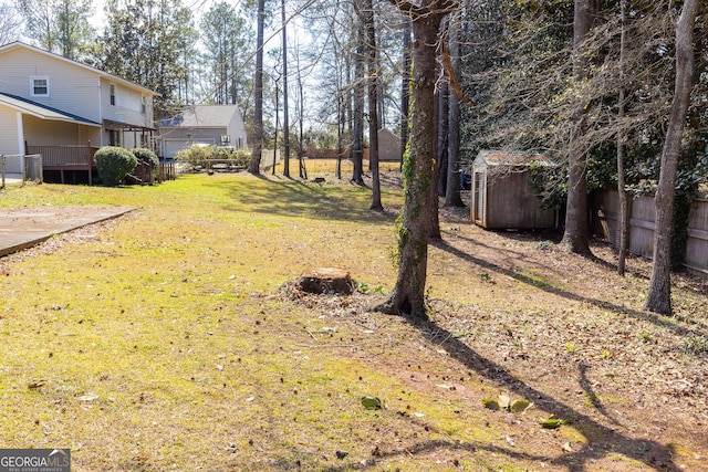 view of yard featuring a storage unit, an outdoor structure, and fence