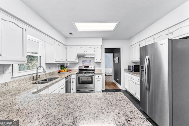 kitchen featuring appliances with stainless steel finishes, sink, dark hardwood / wood-style flooring, white cabinets, and tasteful backsplash