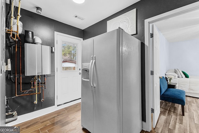 interior space featuring hardwood / wood-style floors, white refrigerator with ice dispenser, and tankless water heater