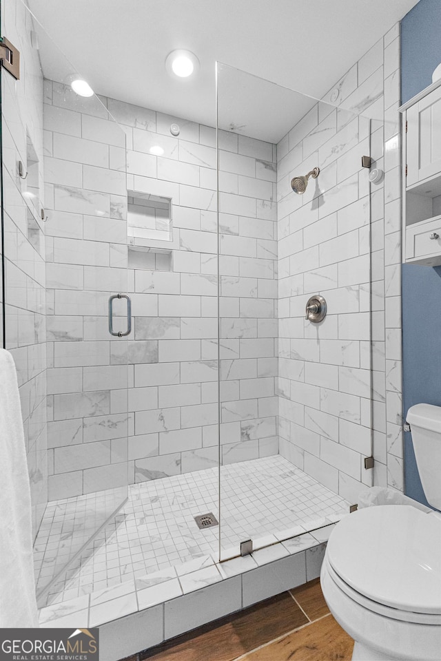 bathroom featuring walk in shower, toilet, and hardwood / wood-style floors