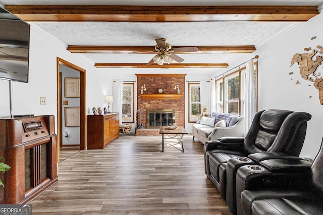 living room with a fireplace, beam ceiling, ornamental molding, wood-type flooring, and a textured ceiling