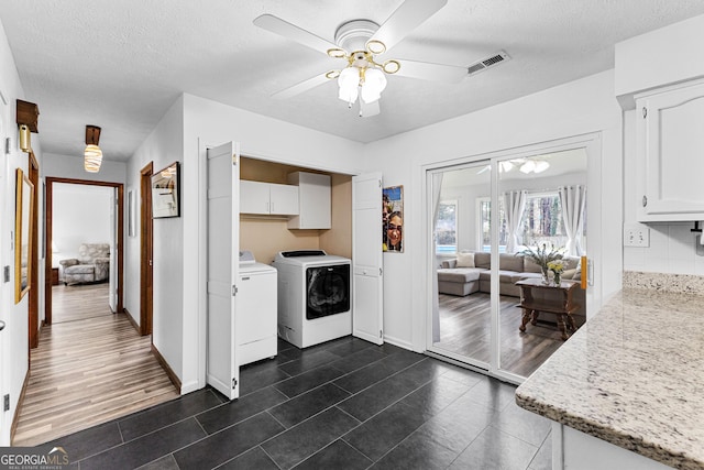 kitchen featuring ceiling fan, white cabinetry, washer and clothes dryer, and a textured ceiling