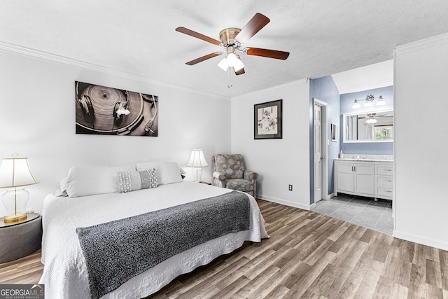 bedroom with connected bathroom, light hardwood / wood-style floors, ornamental molding, ceiling fan, and a textured ceiling