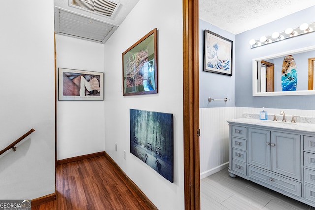 bathroom with hardwood / wood-style flooring, vanity, and a textured ceiling