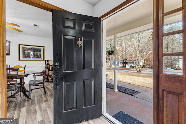 foyer entrance with crown molding, ceiling fan, and light hardwood / wood-style flooring