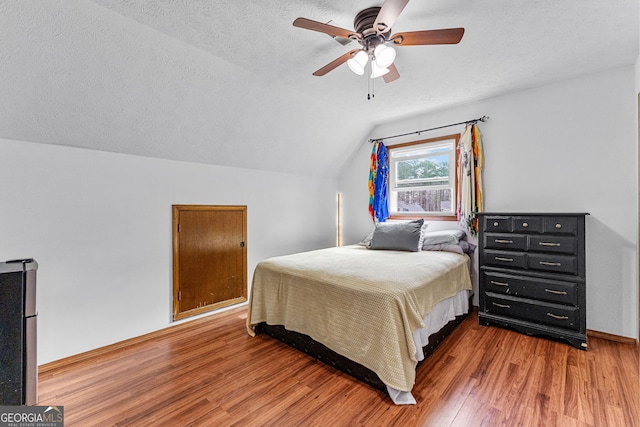 bedroom featuring a textured ceiling, lofted ceiling, hardwood / wood-style floors, and ceiling fan