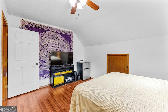 bedroom with stainless steel refrigerator, lofted ceiling, ceiling fan, and hardwood / wood-style flooring