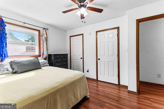 bedroom with ceiling fan, dark wood-type flooring, and a textured ceiling