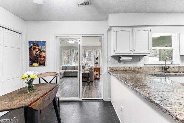 kitchen with white cabinets, light stone countertops, a textured ceiling, and sink