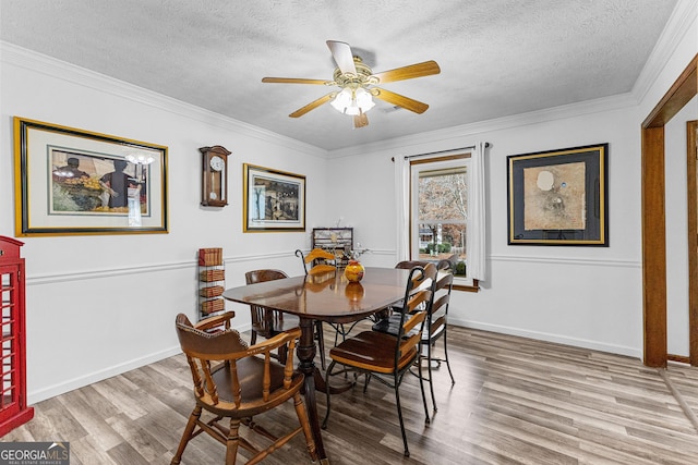 dining area featuring ceiling fan, crown molding, wood-type flooring, and a textured ceiling